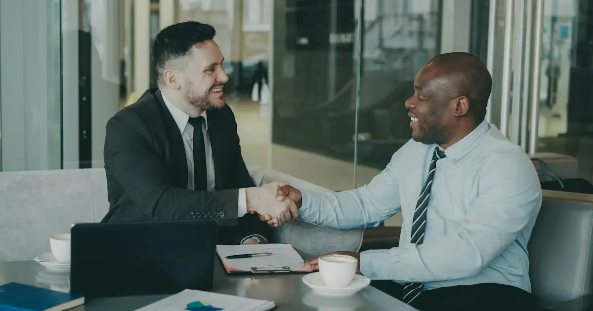 Two business people shaking hands across a desk