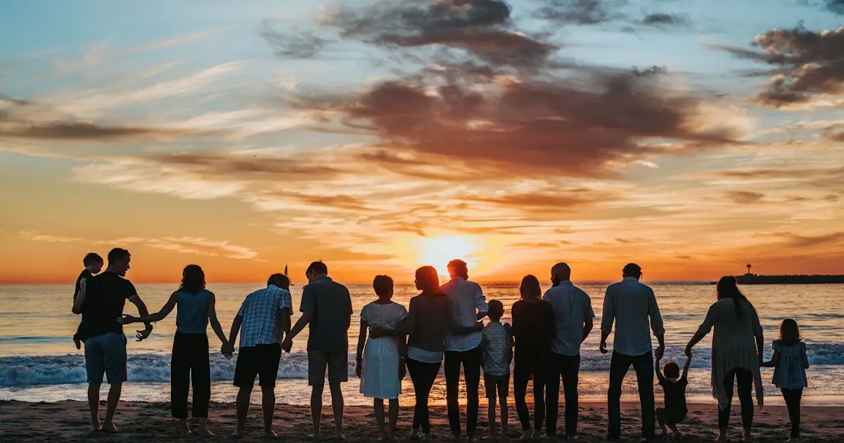 Family standing together on a beach at sunset