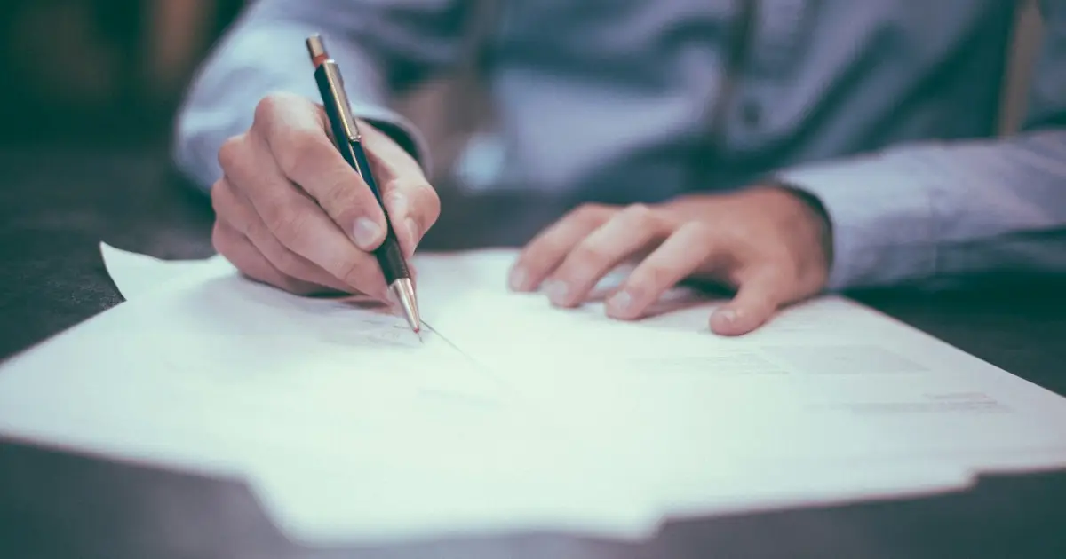 Professional signing a document at a desk